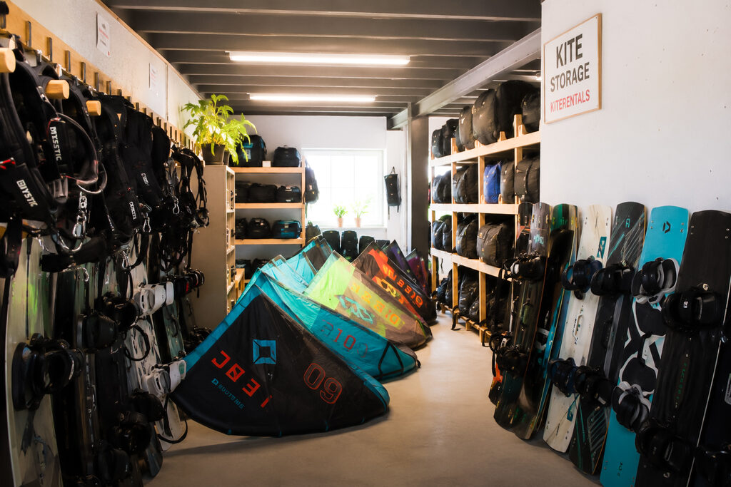 Kite rental storage room with kiteboards, harnesses and kite bags neatly racked